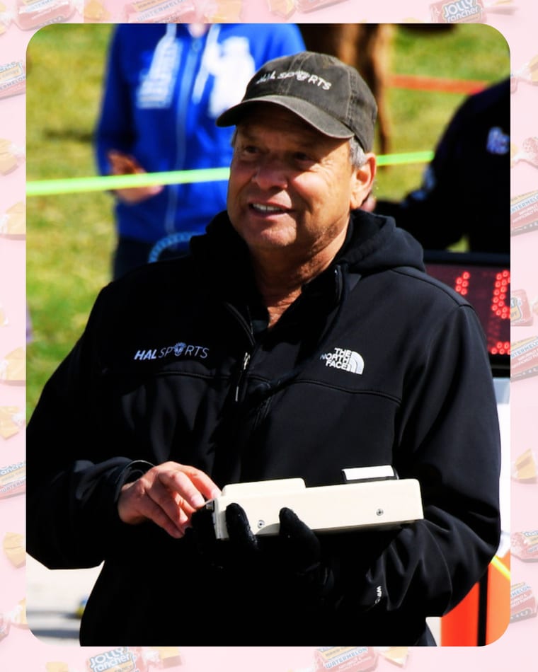 A Hal Sports team member timing runners at The Great Candy Run, framed with Jolly Rancher candy artwork